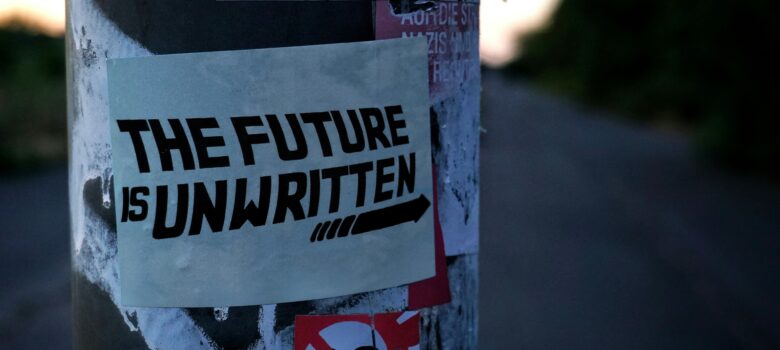A sticker on a street pole that reads "The Future Is Unwritten" Photo by Mac Bohme - found on Unsplash.com