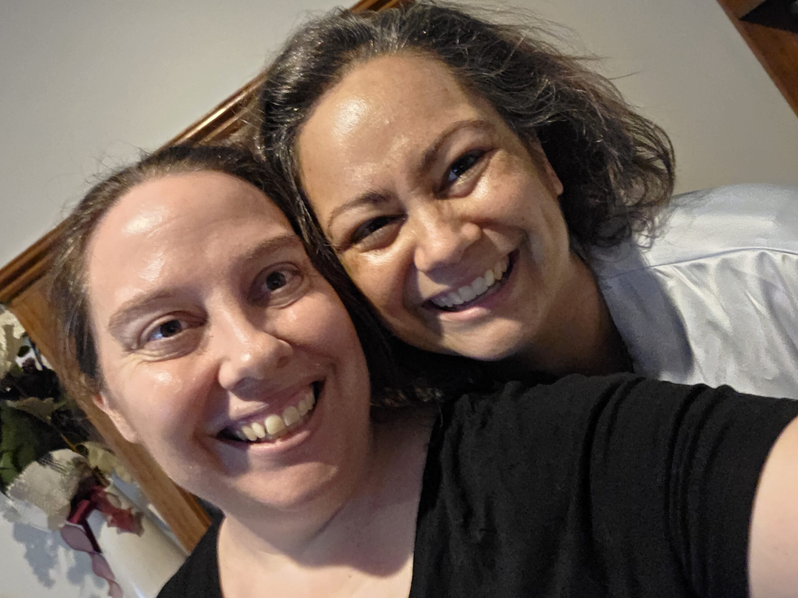 Two women with dark hair and lighter skin smiling at the camera.